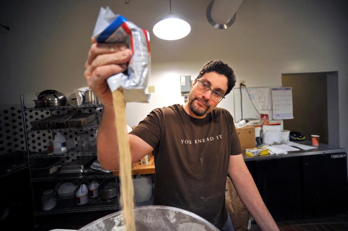 Tony Sapia pours yeast in a bowl while scaling ingredients for a batch of bread at Gemelli Bakery in 2016.