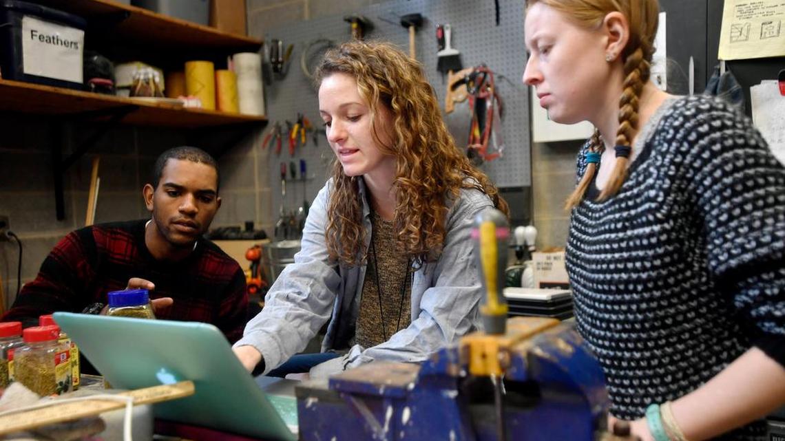 Set designer Abigaile Wiker, center, shows some of her ideas to fellow crew members in the prop shop.