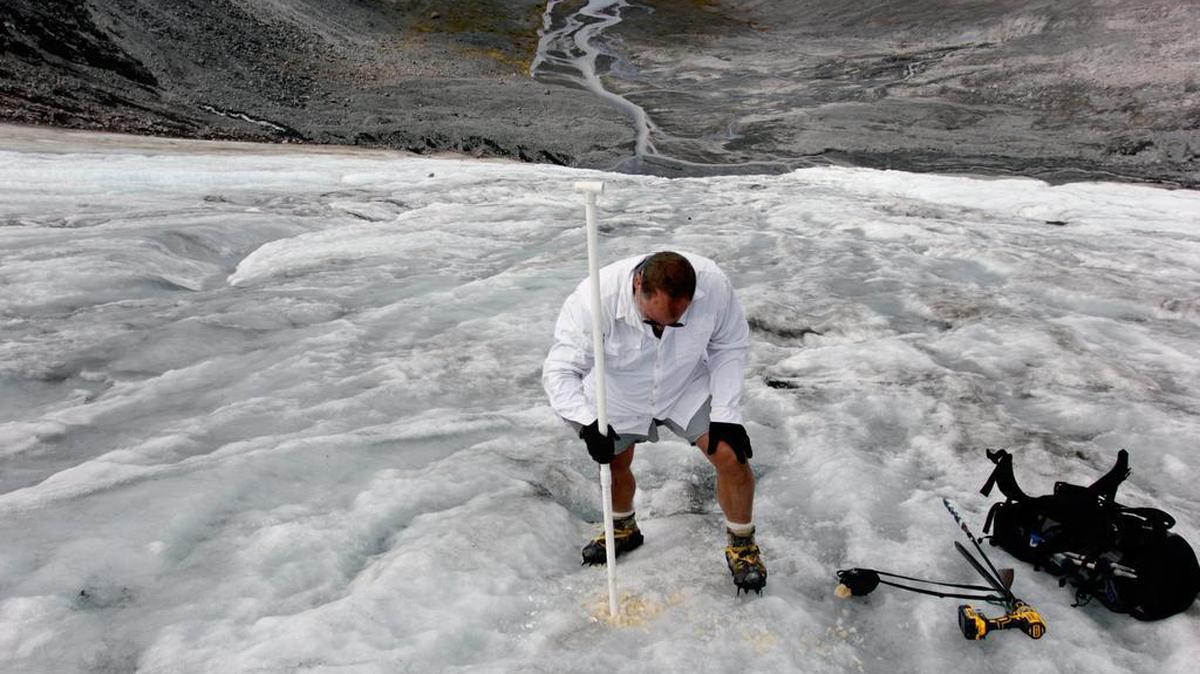 A scientist for the Nooksack Indian Tribe measures ice melt on the Sholes Glacier in Mount Baker, Wash. Glaciers thinning and retreating is just one of the effects of human-made climate change.