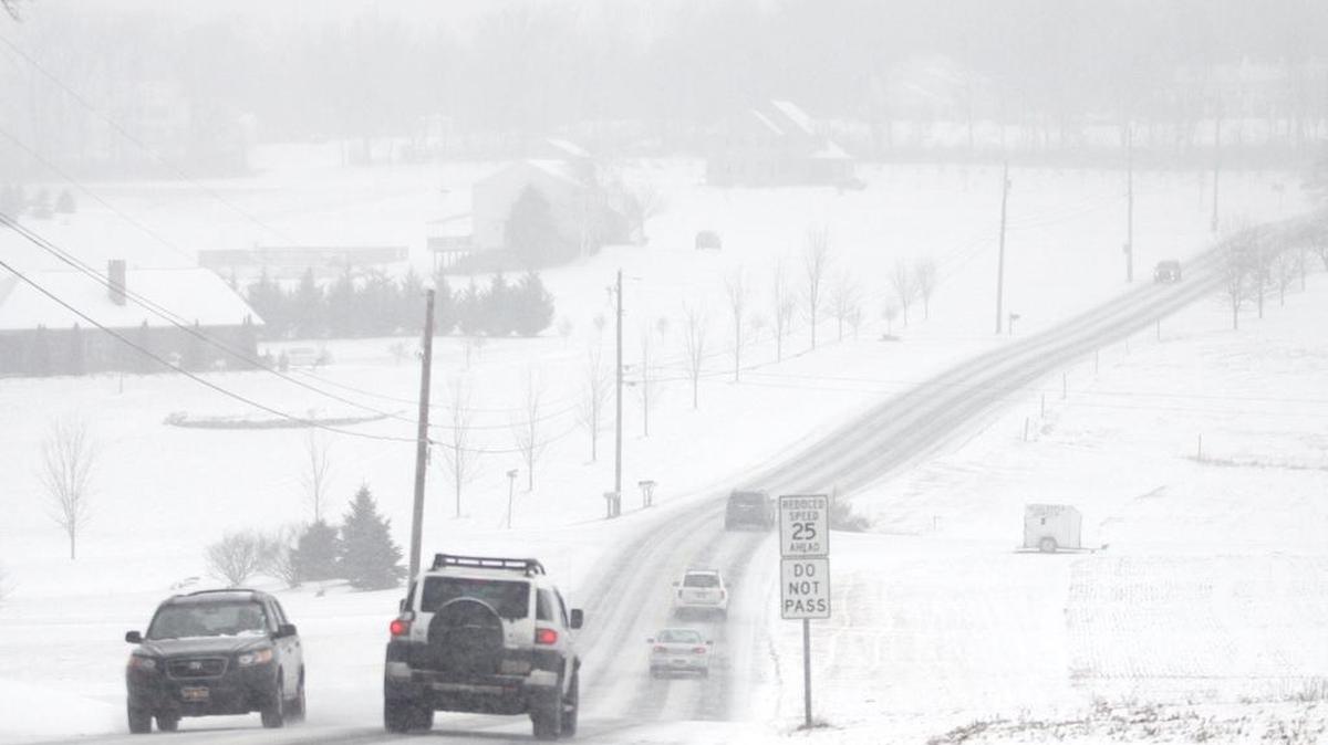 Cars drive along Blanchard Street near Bellefonte as snow begins to fall.