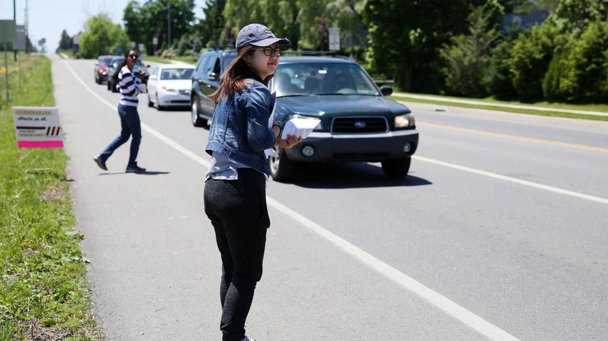 Boya Xiong, right, and Amanda Ramcharan hand out pamphlets describing the Toll Brothers development Saturday along Whitehall Road in Ferguson Township.