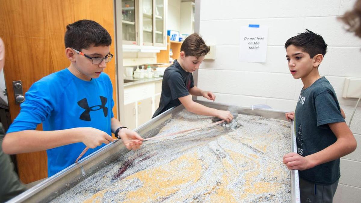 Ferguson Township Elementary fifth graders Tanner Ligetti, far left, Owen Yerka, center, and Zac Meddeb take measurements during an experiment with the stream table during the Shake Rattle Rocks event on Friday, Jan 6, 2017 at the Penn State Deike Building.
