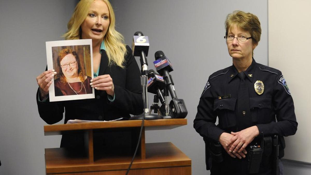 District Attorney Stacy Parks Miller holds a photo of Jean Tuggy as Ferguson Township Police Chief Diane Conrad, right, looks on during a news conference Wednesday.