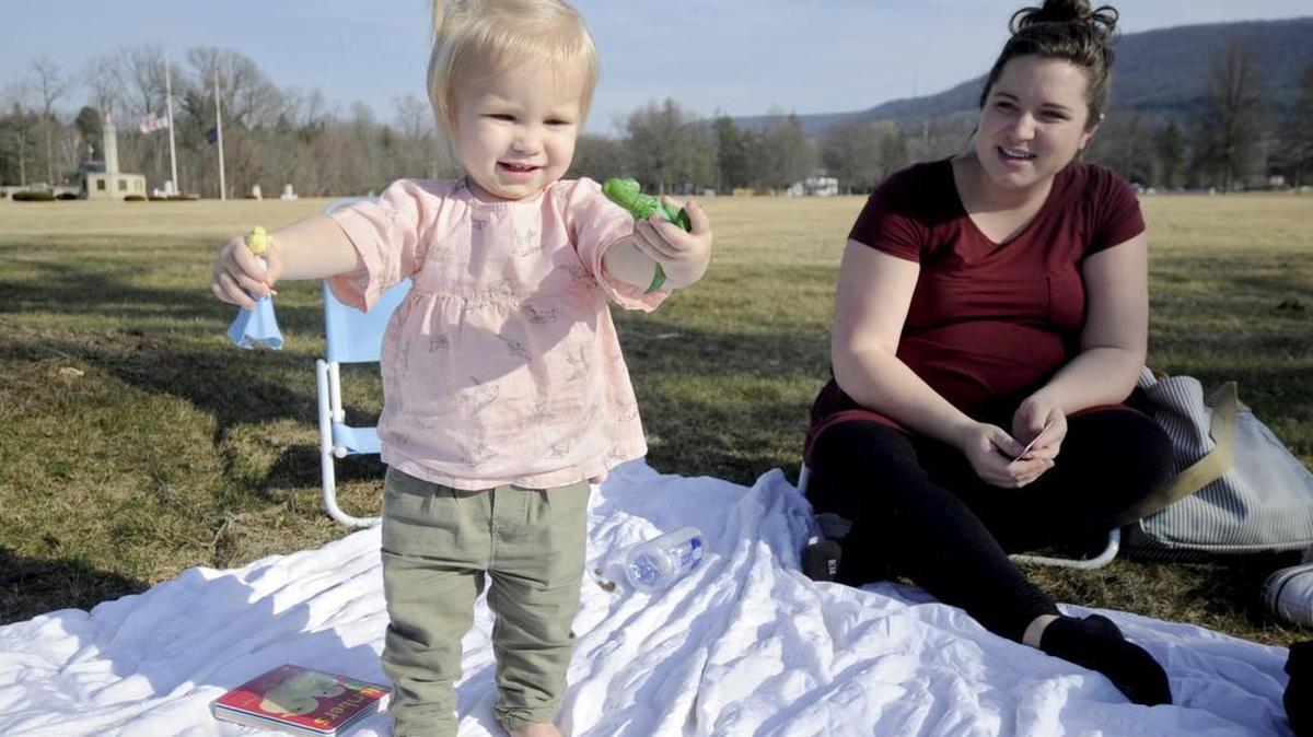 Mya Naatjes, 17 months, shows off her Rex figurine as she enjoys the sunny weather with her parents on the Pennsylvania Military Museum lawn in Boalsburg on Wednesday.