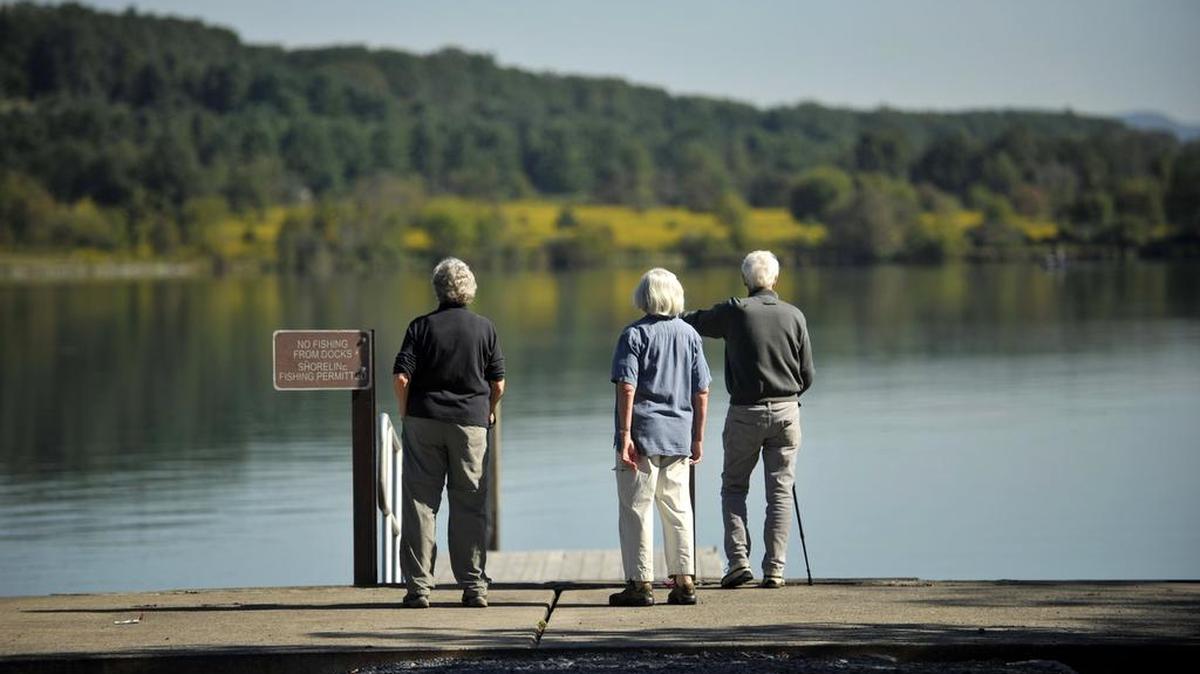 Carolyn Holt, left, Anne Burgos, middle, and Martin Grieco look over the lake before a hike at Bald Eagle State Park. A recently released study by George Mason University shows that Pennsylvania’s local and regional parks annually produce more than $1.6 billion in economic activity.