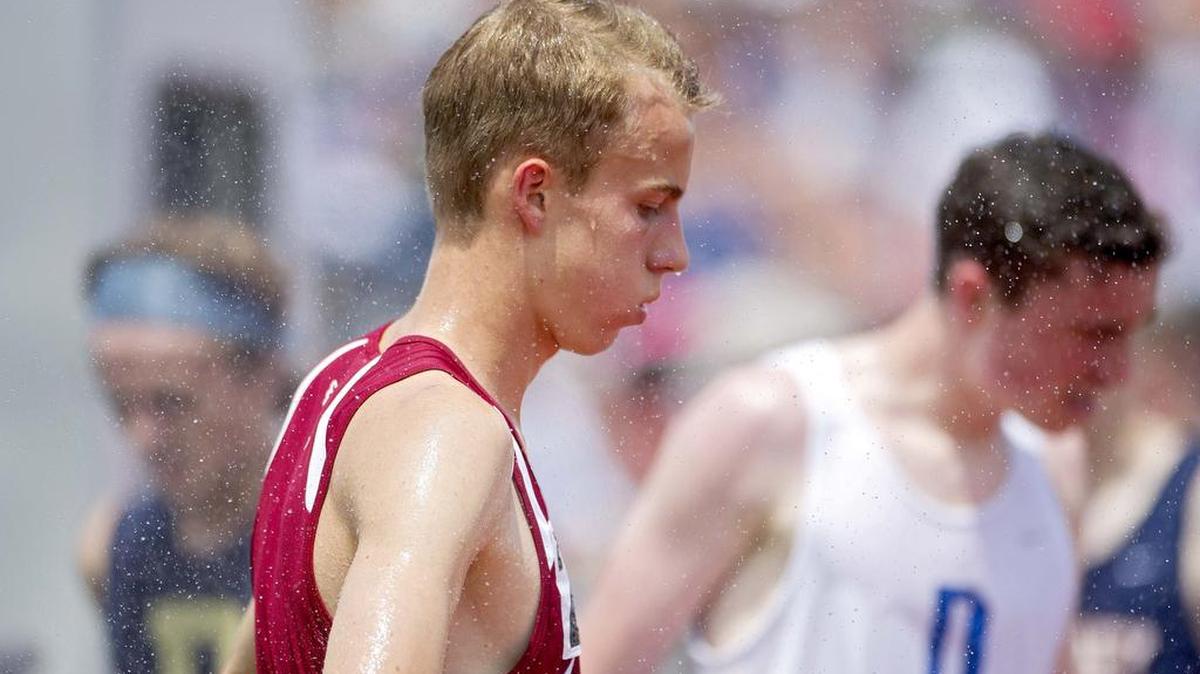 State College's Alex Milligan cools off in the sprinklers after the 1600 meter run during the PIAA State Track and Field and Championships at Shippensburg University on Friday, May 27, 2016.