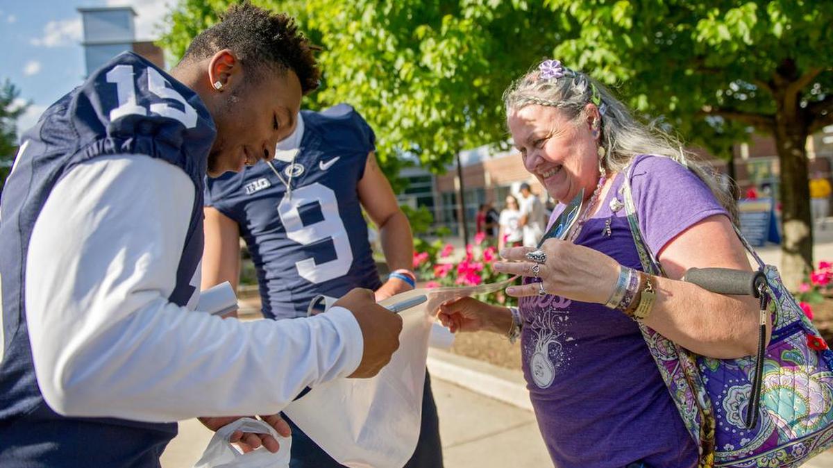 Penn State football’s Grant Haley signs Becky Dwyer's poster as members of the team greet community members last year during the poster handout. This season’s poster delivery will take place on Tuesday.