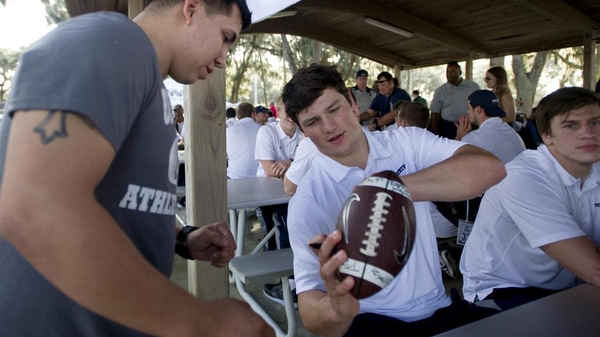 Penn State football quarterback Christian Hackenberg signs a football for QM3 (SW/AW) Anthony Summerour at the Naval Station Mayport on Wednesday, December 30, 2015 as part of the TaxSlayer Bowl week.