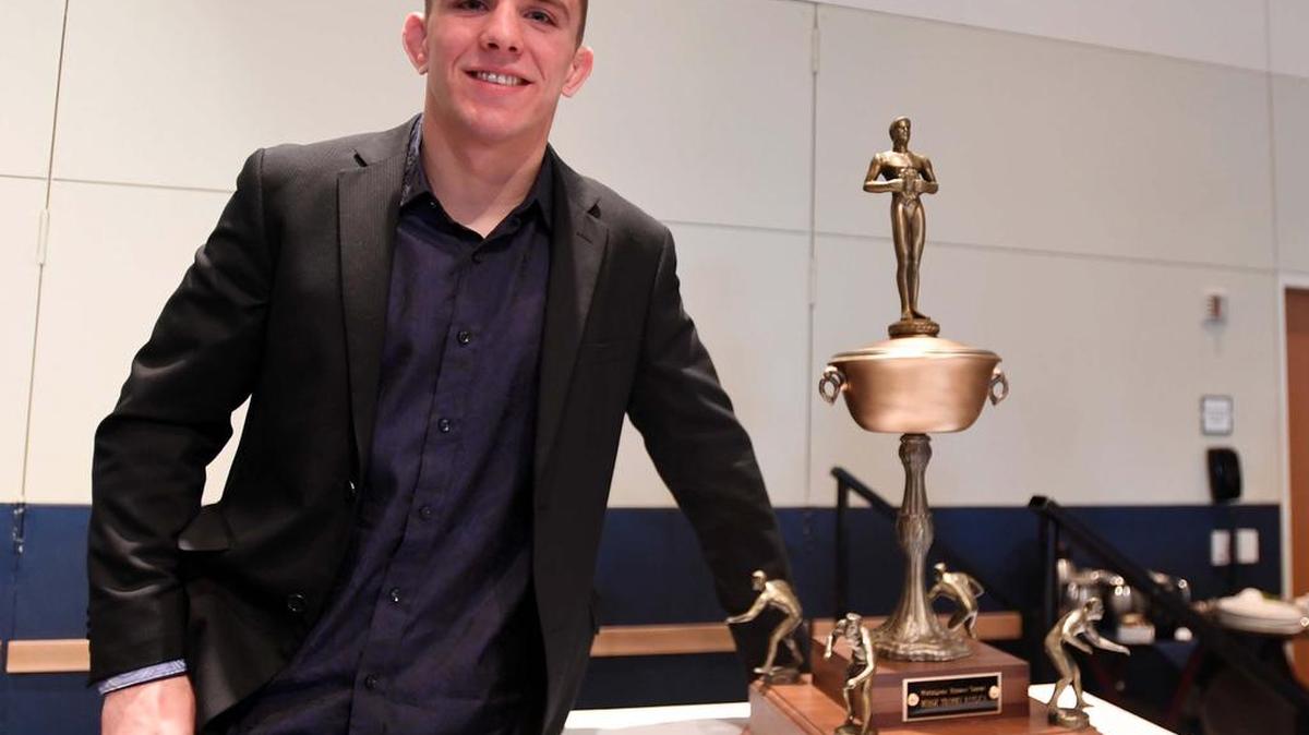 Zain Retherford stands for a portrait next to the Hodge trophy during an awards banquet April 9 at the Penn Stater.