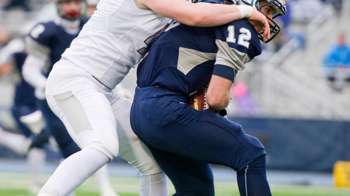 McDowell’s Matt Kelly holds onto the ball while being tackled by State College’s Nathan King during the second half of a PIAA Class AAAA subregional football playoff game at Clarion University of Pennsylvania’s Memorial Stadium on Saturday, Nov. 27, 2015 in Clarion. State College won 48-40.