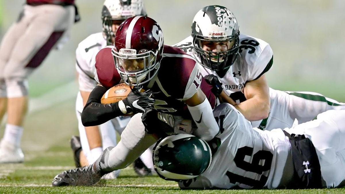 State College’s Brandon Clark is pulled down by Central Dauphin defenders in last season’s contest, when the Little Lions lost 13-10. The two teams will meet again at 7 p.m. Friday.