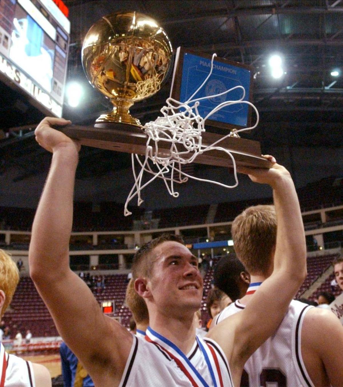 State College’s Willie Morse holds the state title trophy high after defeating Chester in overtime at the PIAA Class AAAA Boys’ Basketball Championship in Hershey on March 22, 2003.