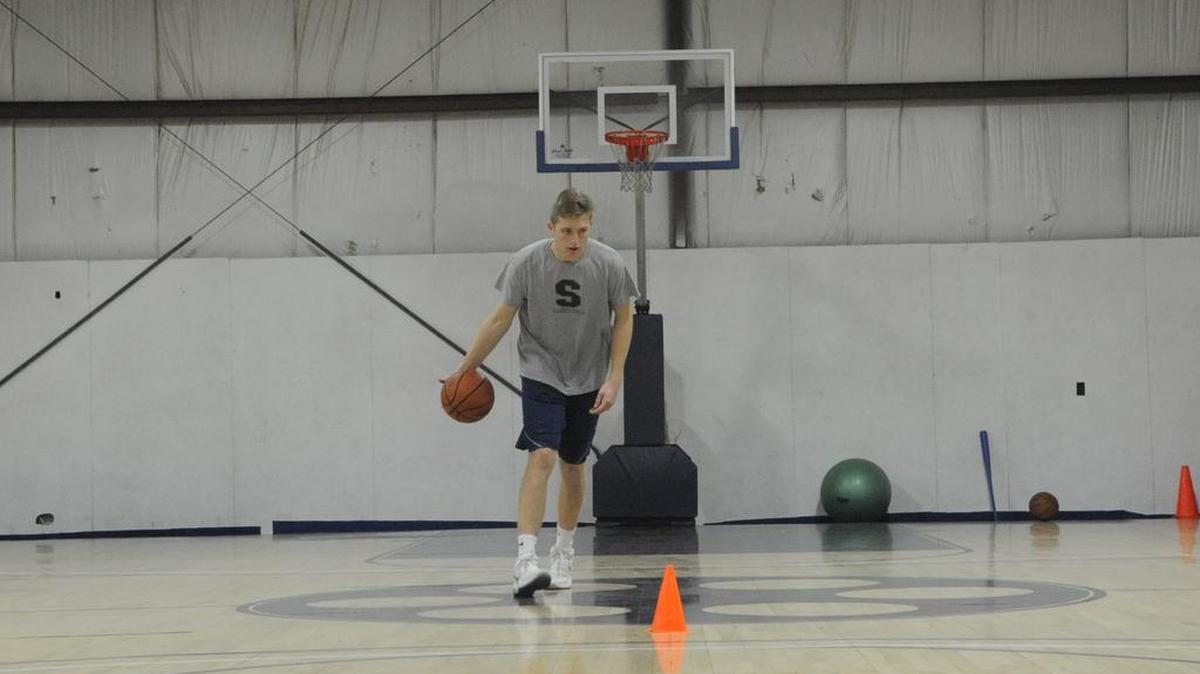 State High junior Drew Friberg works out on the basketball court in a warehouse at Spectra Wood, his family’s business.