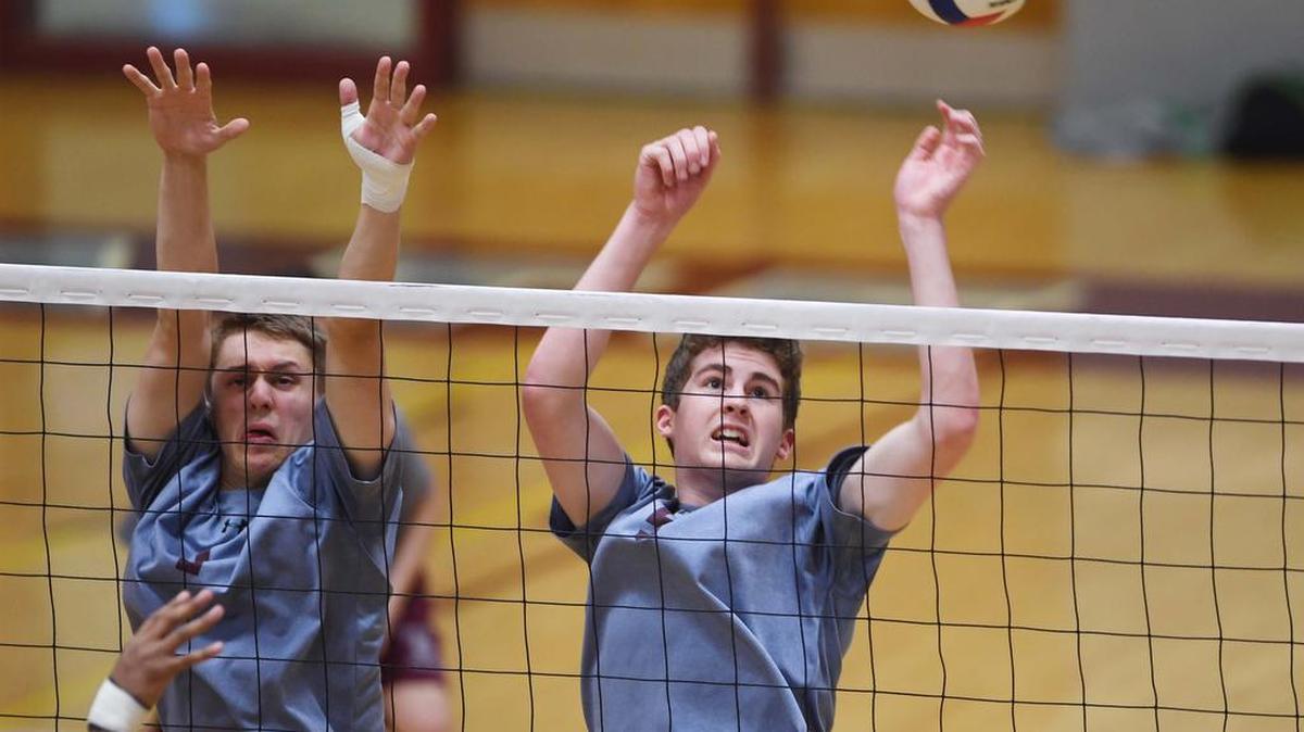 State College middle blocker Nate Reinart, left, and outside hitter Joe McCracken reach up to block the ball during a game against Central Dauphin East Thursday, at State College Area High School.