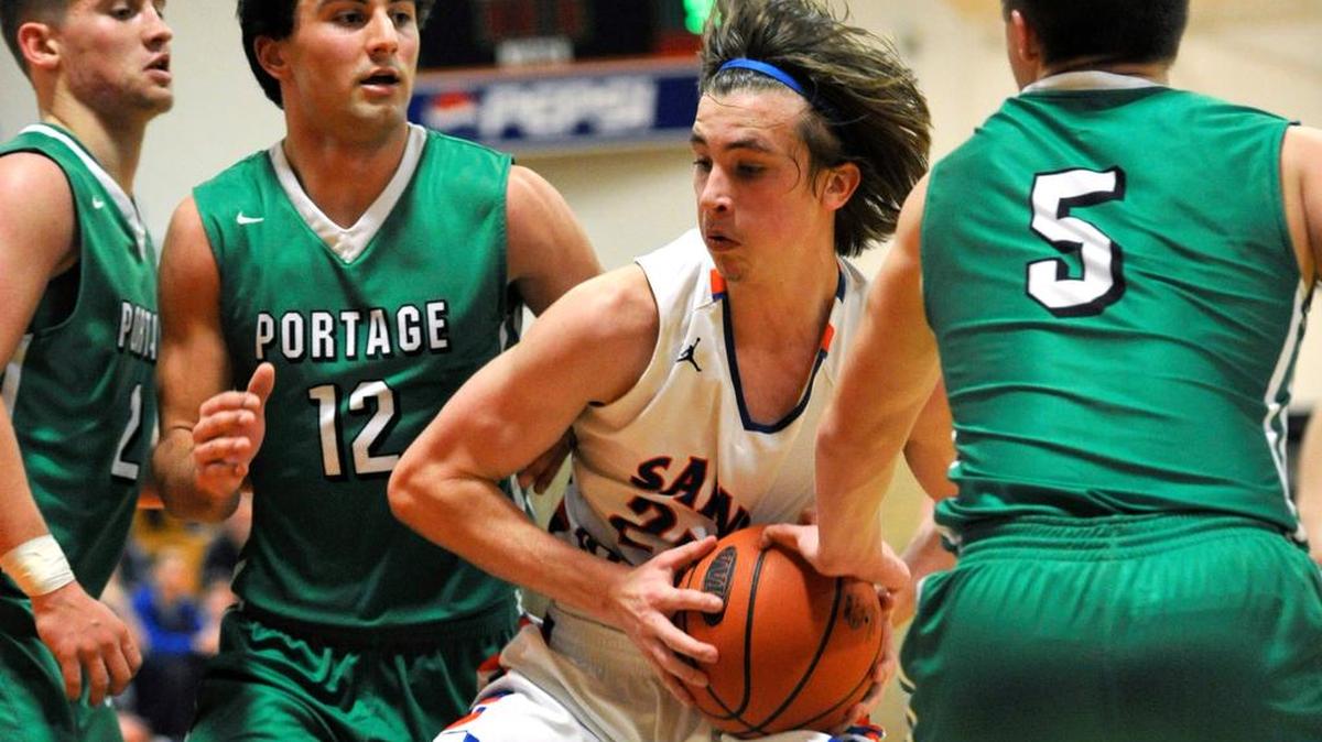 St. Joseph’s Catholic Academy’s Stephen Beattie, center, drives past a trio of Portage defenders. Beattie became the first player in Wolves’ history to record 1,000 career points in their 49-33 loss to the Mustangs in the District 6 Class A first round playoff game on Moday.