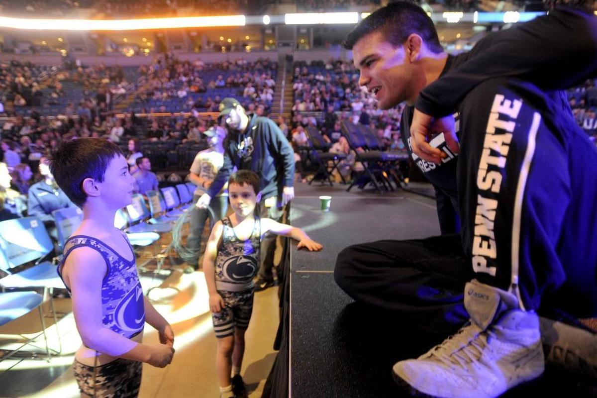 James Whitbred, left, and his brother Jon, middle, talk to Penn State wrestler Morgan McIntosh before a match in February 2016. Whitbred was 7 at the time, and now is a junior at State College.
