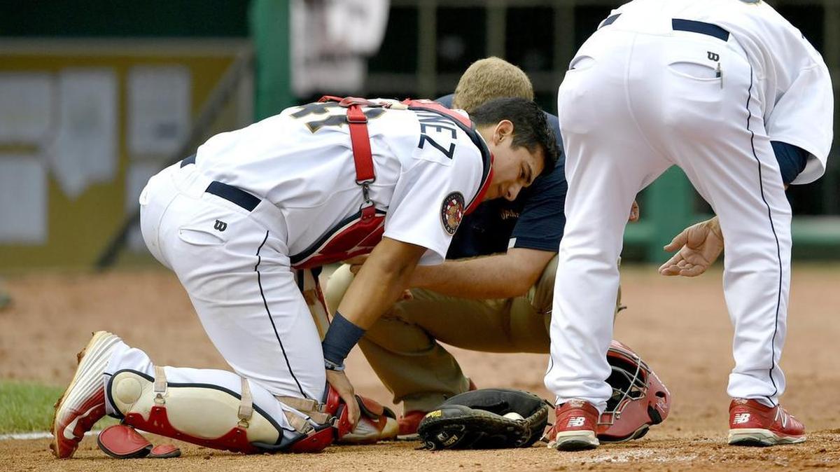 Trainer Chris Whitman helps State College Spikes' catcher Jeremy Martinez during the Thursday, August 11, 2016 game against West Virginia.