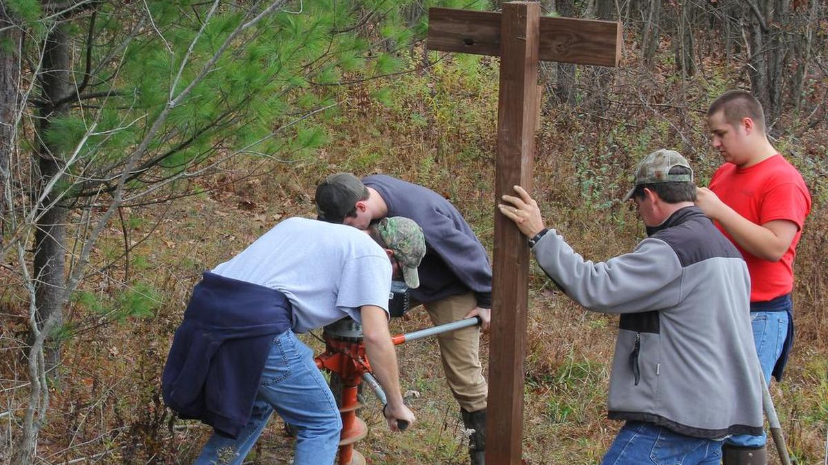 Students Ryan Klinedinst and Dylan Bakner dig a hole as Joe Harding and student Ryan Shelmire wait to install it.