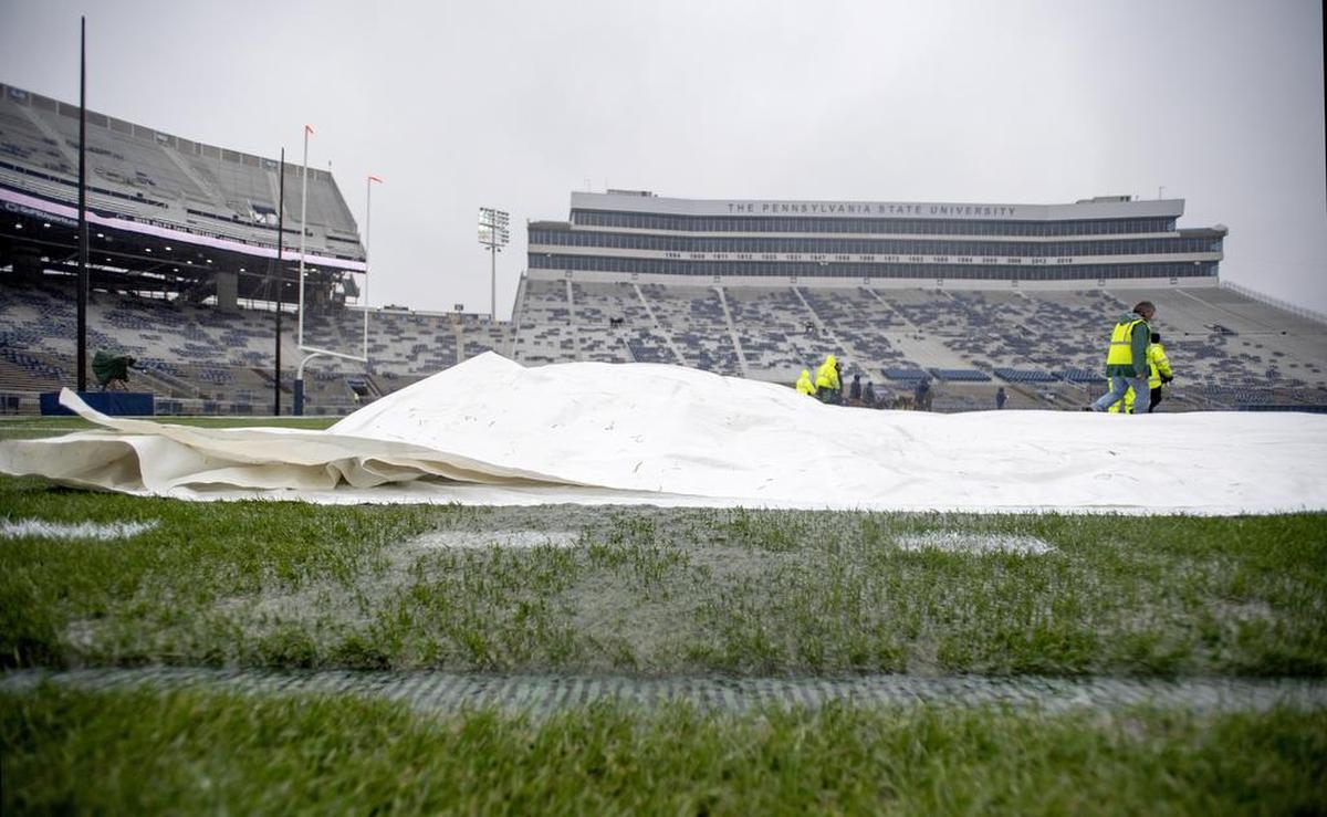 Water pours out off the tarps as the grounds crew pulls them off the field at Beaver Stadium for the Penn State game against Iowa on Saturday, Oct. 27, 2018.